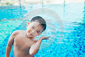 Cute asian kid cleaning ears after swimming in a pool