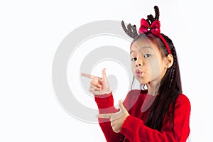 Cute asian kid girl in red sweater wear reindeer horns headband posing fingers pointing to your text