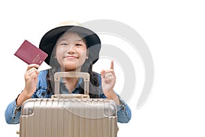Cute asian kid ready to travel wearing a hat and holding her passport with luggage isolated