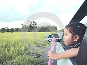 Cute asian little child girl blowing bubble out of car window