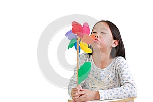 Cute Asian little child girl blowing colorful pinwheel isolated on white background. Kid hold and playing windmill in hand