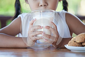 Cute asian little child girl is drinking a milk from glass