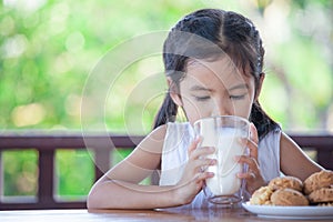 Cute asian little child girl is drinking a milk from glass