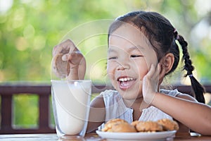 Cute asian little child girl eating cookie with milk