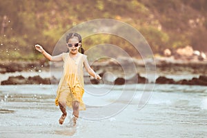 Cute asian little child girl having fun to play and run on beach