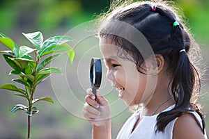 Cute asian little child girl looking through a magnifying glass