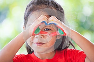 Cute asian little child girl with painted hands make heart shape colorful