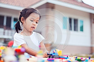 Cute asian little child girl playing with colorful toy blocks