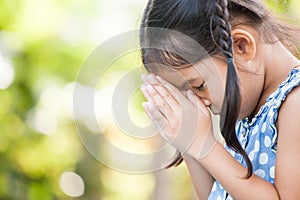 Cute asian little child girl praying with folded her hand