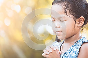 Cute asian little child girl praying with folded her hand