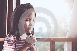 Cute asian little child girl praying with folded her hand