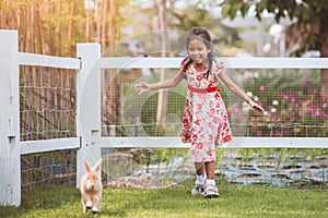 Cute asian little child girl running to catch a rabbit with fun