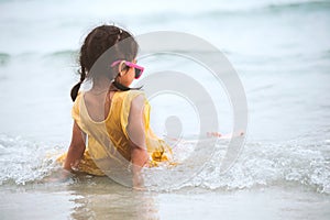 Cute asian little child girl sitting and playing on beach