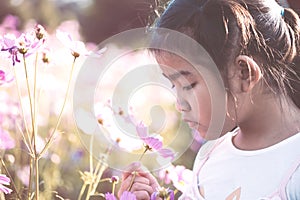 Cute asian little child girl smelling cosmos flower