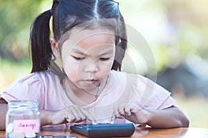 Cute asian little child girl using calculator