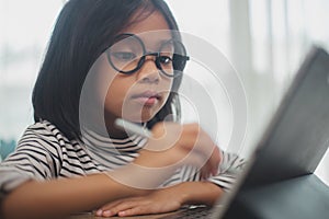 Cute Asian little girl children using a laptop computer, studying through an online e-learning system