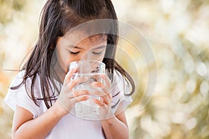 Cute asian little girl drinking fresh water from glass
