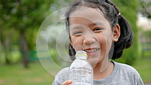 Cute Asian little girl drinking water with happiness at nature public park