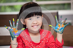 Cute asian little girl with hands in paint , in classroom school  concept - happy children showing painted hand palms at preschool