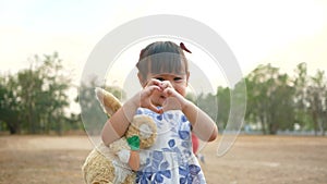 Cute Asian little girl hugging rabbit doll with smiley face in public park.