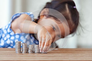 Cute asian little girl playing with coins making stacks of money