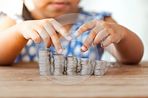 Cute asian little girl playing with coins making stacks of money