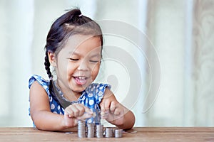 Cute asian little girl playing with coins making stacks of money