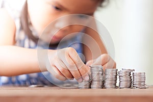 Cute asian little girl playing with coins making stacks of money