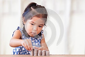 Cute asian little girl playing with coins making stacks of money