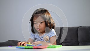 Cute Asian little girl playing with colorful toy ABC jigsaw, Kids play with educational toys at kindergarten or daycare. Creative