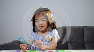 Cute Asian little girl playing with colorful toy ABC jigsaw, Kids play with educational toys at kindergarten or daycare. Creative