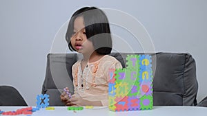 Cute Asian little girl playing with colorful toy ABC jigsaw, Kids play with educational toys at kindergarten or daycare. Creative