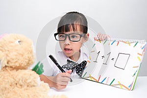 Cute Asian little girl playing teacher role game. A little girl is teaching math to her teddy bear friend. Homeschool children`s