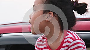 Cute asian little girl smiling and having fun to travel by car and looking out of the car window. Happy family enjoying road trip