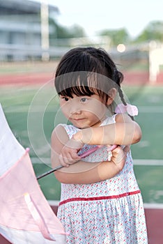 Cute Asian little girl is smiling while holding a pink umbrella
