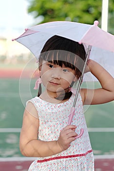 Cute Asian little girl is smiling while holding a pink umbrella