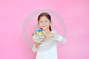 Cute asian little kid girl holding a globe with pointing Thailand at map on earth isolated over pink background. Portrait of child