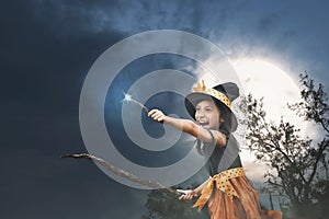 Cute asian little witch girl with magic wand on her hands