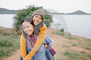 Cute Asian mother and daughter  piggyback ride on her back with the laughing  at river in the morning. The concept of  family  tou photo