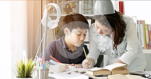 Cute asian mother helping your son doing your homework .