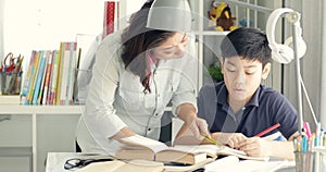 Cute asian mother helping your son doing your homework .