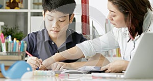 Cute asian mother helping your son doing your homework .