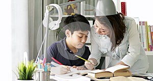 Cute asian mother helping your son doing your homework at home with smile face together.