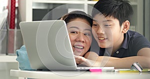 Cute asian mother helping your son doing your homework at home with smile face together.