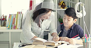 Cute asian mother helping your son doing your homework at home with smile face together.