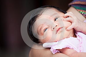 Cute asian newborn baby girl resting on mother`s arm