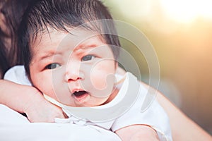 Cute asian newborn baby girl resting on mother`s shoulder