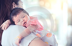 Cute asian newborn baby girl resting on mother`s shoulder