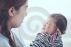 Cute asian newborn baby girl sleeping on mother`s hand.