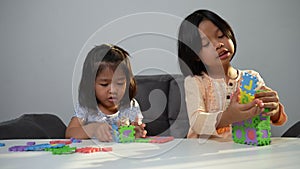 Cute Asian sister same pregnant siblings playing with colorful toy ABC jigsaw, Kids play with educational toys for brain